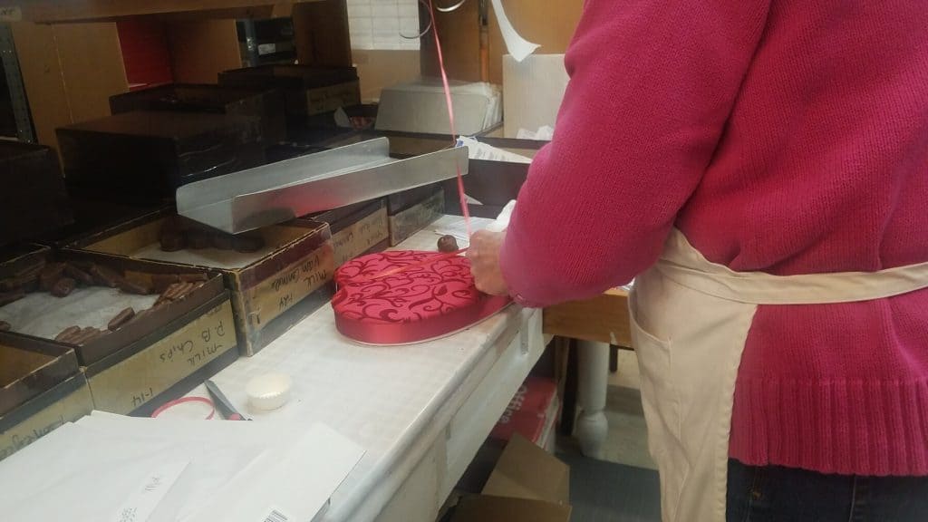 Janet Wittich Ties a Ribbon around a Heart Shaped Box for Valentine's Day