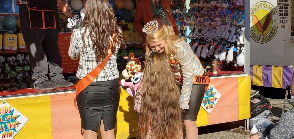 Miss Pumpkin Show kneeling down to talk with Little Miss